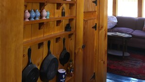 Een houten interieur met planken waarop borden en keukengerei staan.