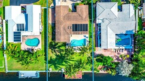 Zona residencial con piscina, palmeras y casas de diversos estilos arquitectónicos.