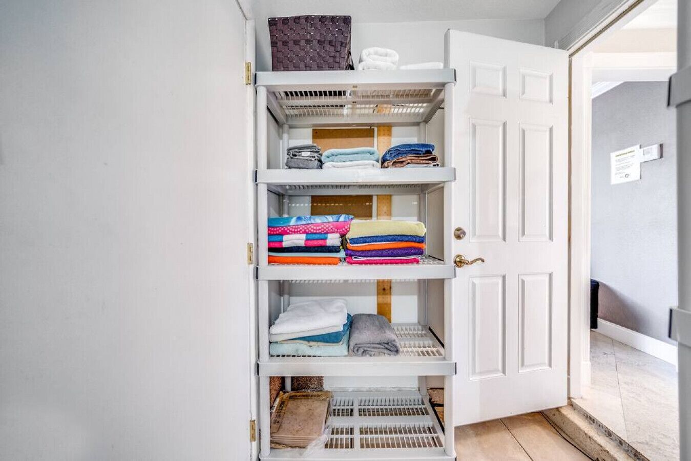 A walk-in closet with multiple shelves for folded clothes and a small storage bin at the bottom.