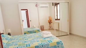 Ein Schlafzimmer mit Bett, Spiegel, Heizkörper und Fenster.