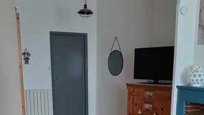 Ein Wohnzimmer mit einer Couch, einem Holztisch, einem Fernseher auf einem Schrank und einem Kamin.