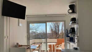 Una cuina moderna amb zona de menjador, un televisor penjat a la paret i vista cap a l'exterior.