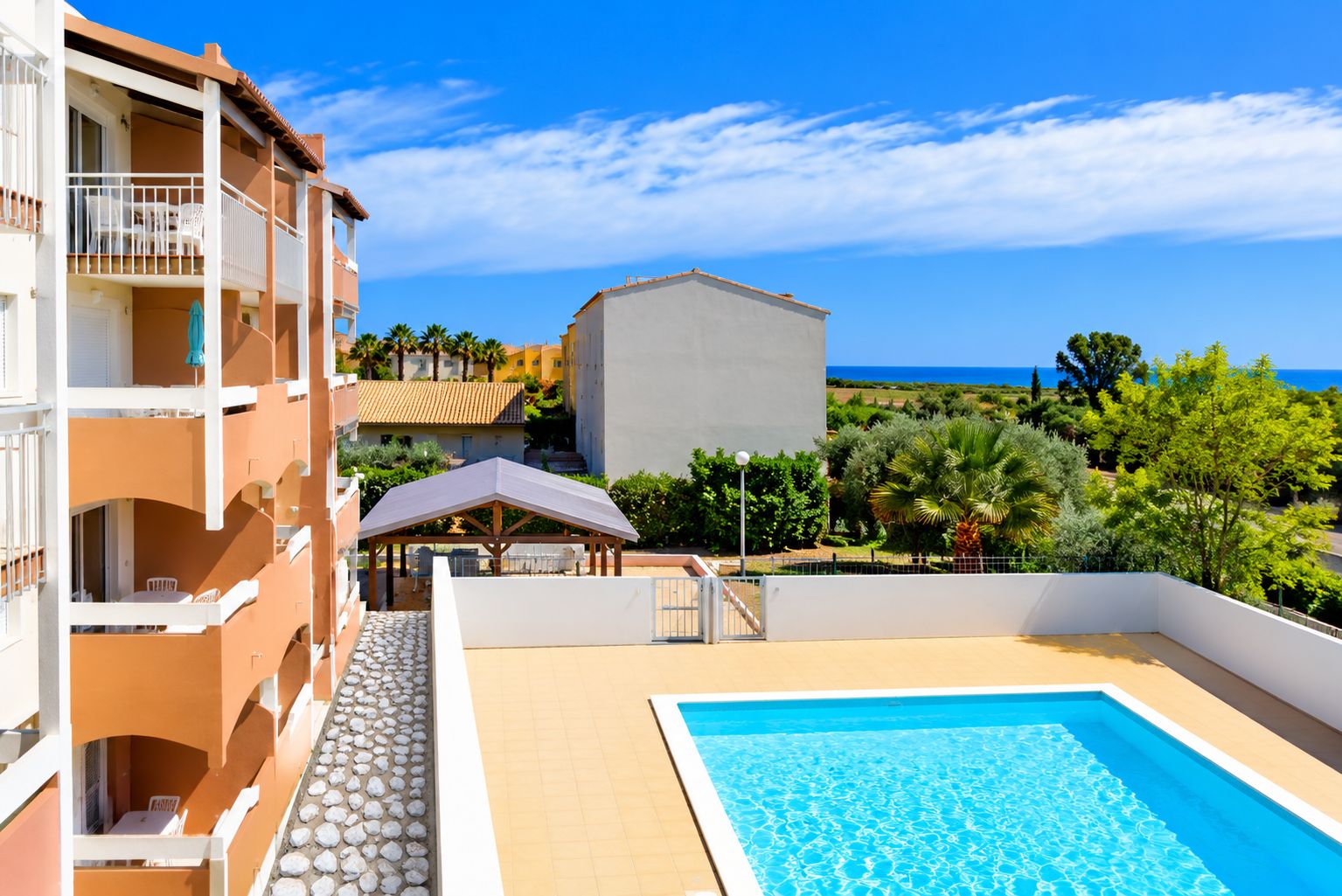 A hotel with a swimming pool, outdoor seating, and a view of the sea.