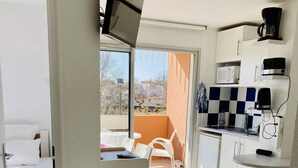 Habitació d'hotel moderna amb un balcó, una cuineta i un llit.
