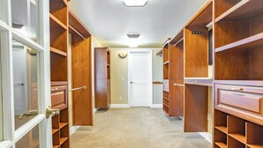 A walk-in closet with multiple wooden shelves and drawers, a white door at the end, and a light fixture on the ceiling. - Spacious 3BR Extended Stay: Airport, Downtown, Ski (North Salt Lake)