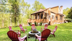 A large wooden house with a deck and a fire pit surrounded by red Adirondack chairs. - Modern, Magical Woodsy Escape 1 Hour From NYC (Putnam Valley)
