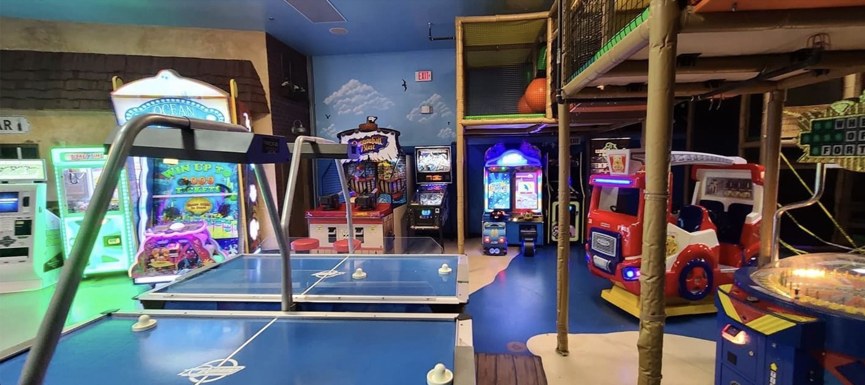 An indoor arcade with various gaming machines, including a basketball game and a racing game.