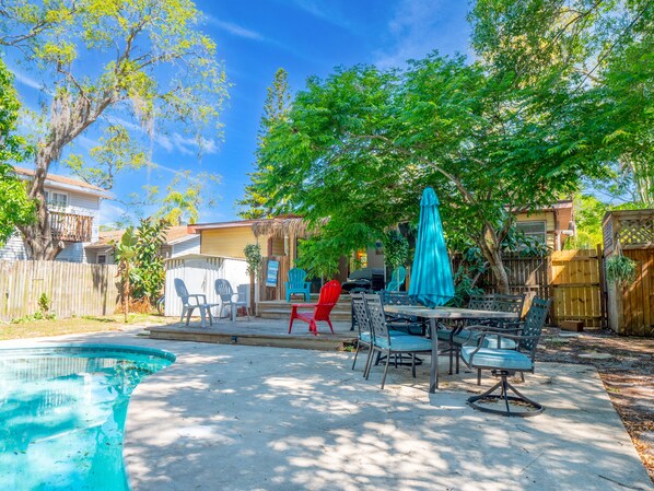 A backyard with a swimming pool, patio furniture, and a wooden fence.