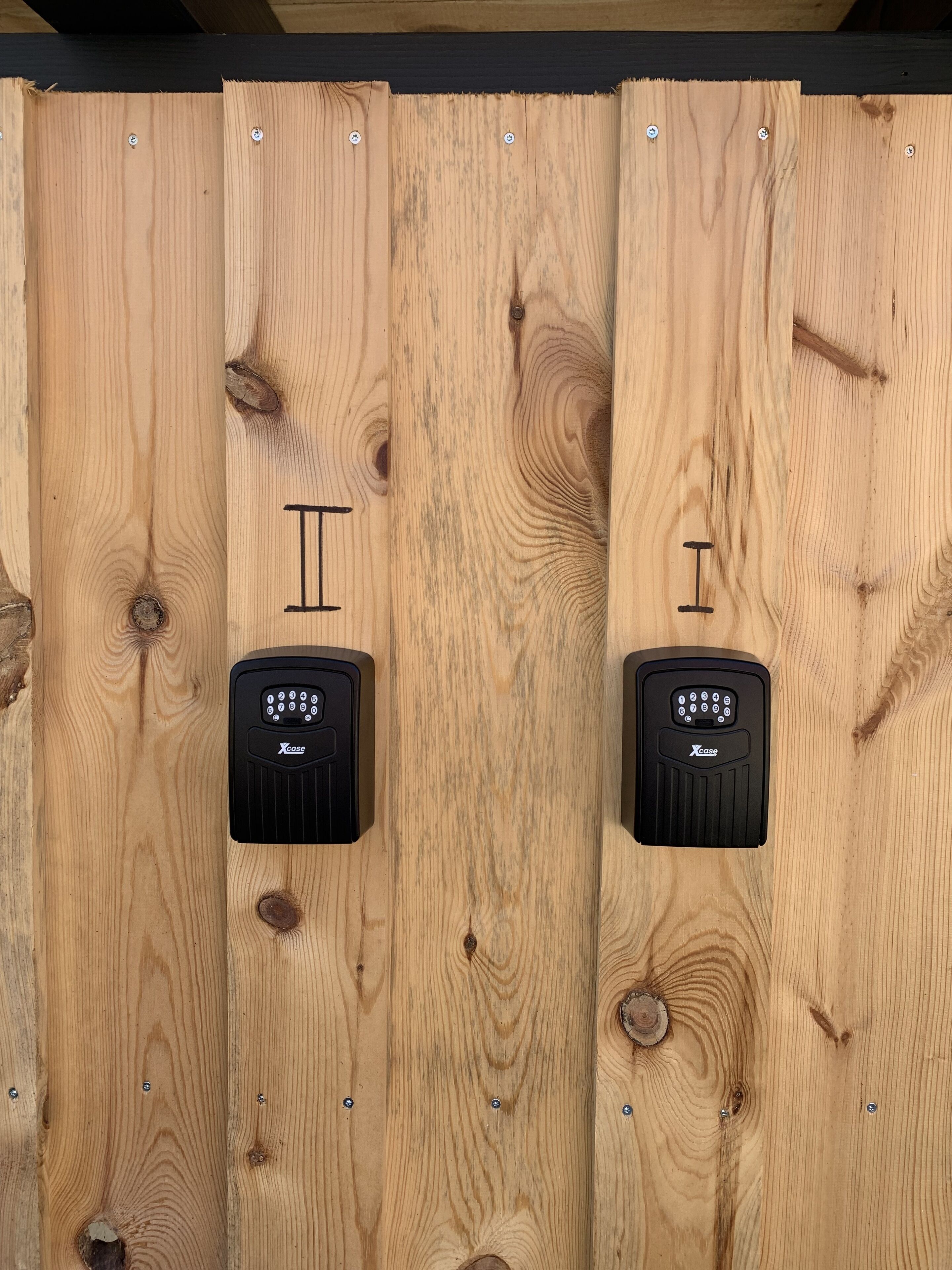 A wooden panel wall with two black electronic devices mounted on it.