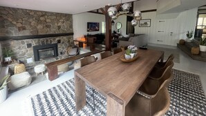 A spacious living area with a stone fireplace, wooden dining table, and a cozy seating arrangement. - Modern Rustic 5 Bedroom Home In the Foothills of the Catskills Mountains. 5 ⭐️ (Otego)