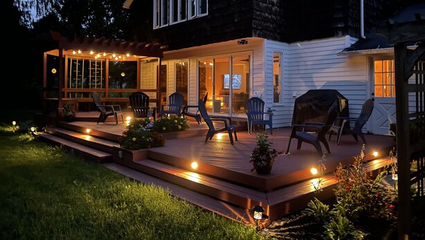 A house with a covered patio, outdoor seating, and a television visible inside. - Modern Rustic 5 Bedroom Home In the Foothills of the Catskills Mountains. 5 ⭐️ (Otego)