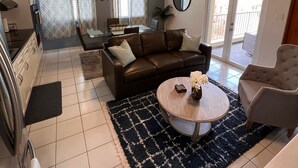 Un salon moderne avec un canapé en cuir marron, une table basse ronde et un ventilateur de plafond.