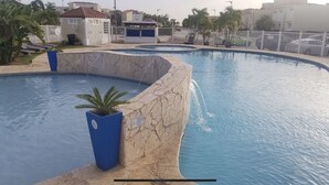 Une piscine au design incurvé, entourée d’un mur de pierre et agrémentée d’un petit palmier.