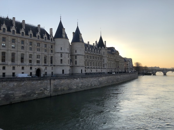 A historic building with multiple towers and a river in the foreground. - In the heart of historic Paris, next to Notre Dame—charm and sophistication. Air-conditioned (Paris)