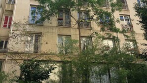 Un immeuble à plusieurs étages, doté de balcons et de fenêtres, avec un arbre au premier plan.