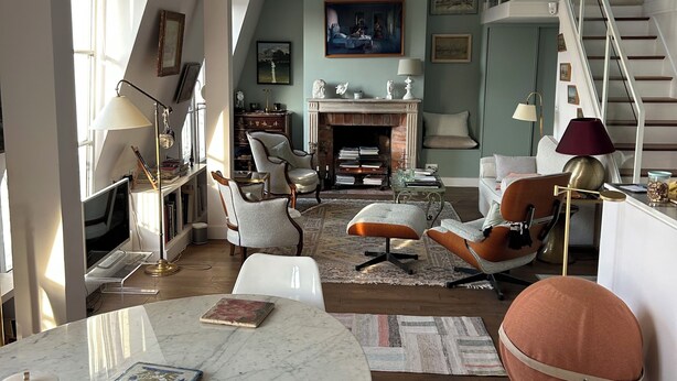 Un vaste salon doté d’un haut plafond, d’une cheminée et d’un escalier menant à un niveau supérieur.