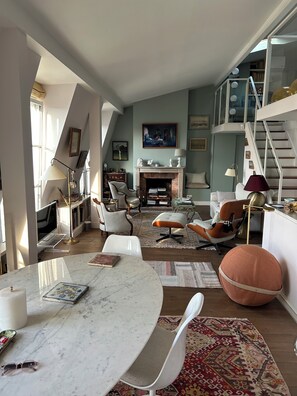 A spacious living room with a high ceiling, a fireplace, and a staircase leading to an upper level. - In the heart of historic Paris, next to Notre Dame—charm and sophistication. Air-conditioned (Paris)