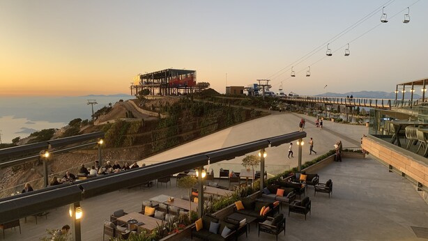 Un espace extérieur aménagé avec des tables et des chaises, offrant une vue panoramique sur l’océan et un bâtiment en construction.