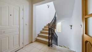 Un escalier avec une rampe en métal noir menant à un palier.