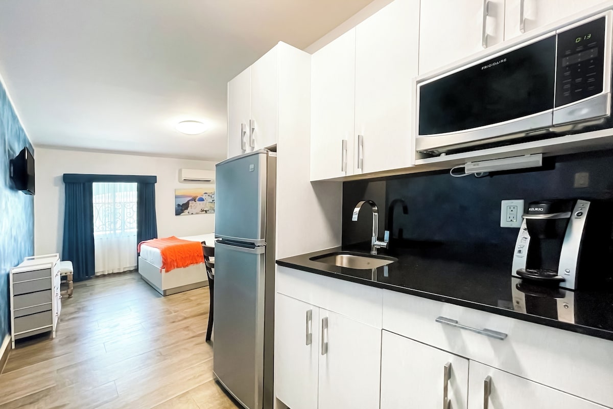 Una cocina moderna con un refrigerador de acero inoxidable, un microondas integrado y una cafetera Keurig.