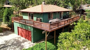 Une maison à deux étages avec un balcon, un garage et un jardin arboré à l’arrière.