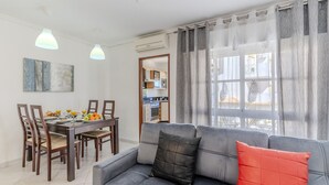 A modern living room with a grey sofa, wooden dining table, and chairs. - #075 T1 Solar by Home Holidays (Albufeira)