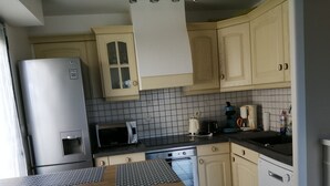A kitchen with a refrigerator, microwave, stove, and cabinets. - Bright, sea-view apartment with direct beach access (Roscoff)