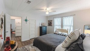 Un dormitorio con cama, cómoda y ventilador de techo.