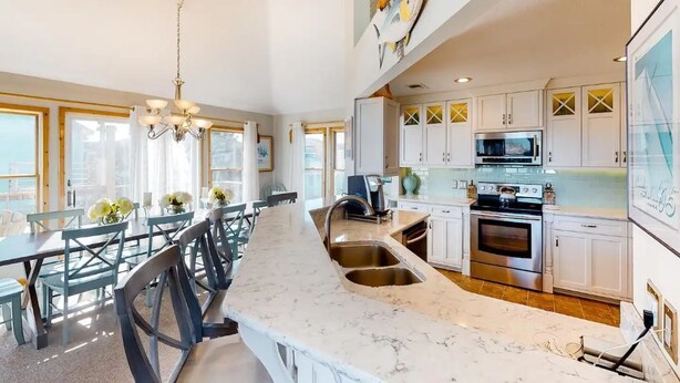 A spacious kitchen with a large island, stainless steel appliances, and a view of the city. - Semi Oceanfront 5 bedroom dog friendly cottage 10 feet to beach access (Corolla)