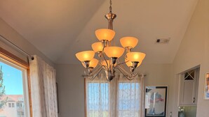 A dining room with a long table, chairs, a chandelier, and a vase with flowers. - Semi Oceanfront 5 bedroom dog friendly cottage 10 feet to beach access (Corolla)