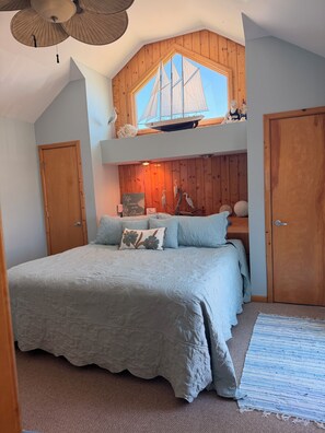 Una camera da letto con un letto grande, soffitto in legno e decorazione a tema vela.