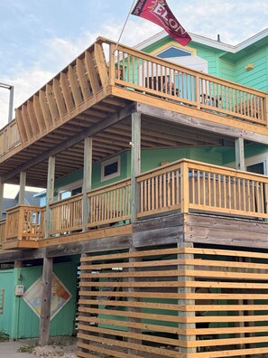 Una struttura in legno a più livelli con balconi, una bandiera e un edificio verde sullo sfondo.
