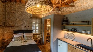 Une chambre à coucher de style rustique, avec un lit, une table de chevet et un petit coin cuisine.