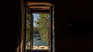 Une porte ouverte donne sur un paysage où l’on aperçoit une étendue d’eau, des arbres et des rochers.