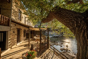 A stone building with a balcony overlooking a river.