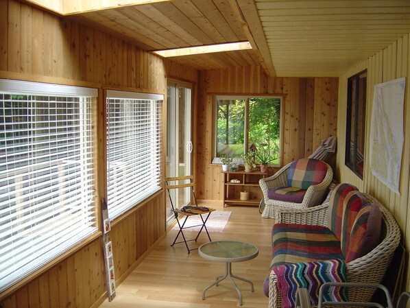 A wooden cabin interior with a sofa, chairs, and a small table.