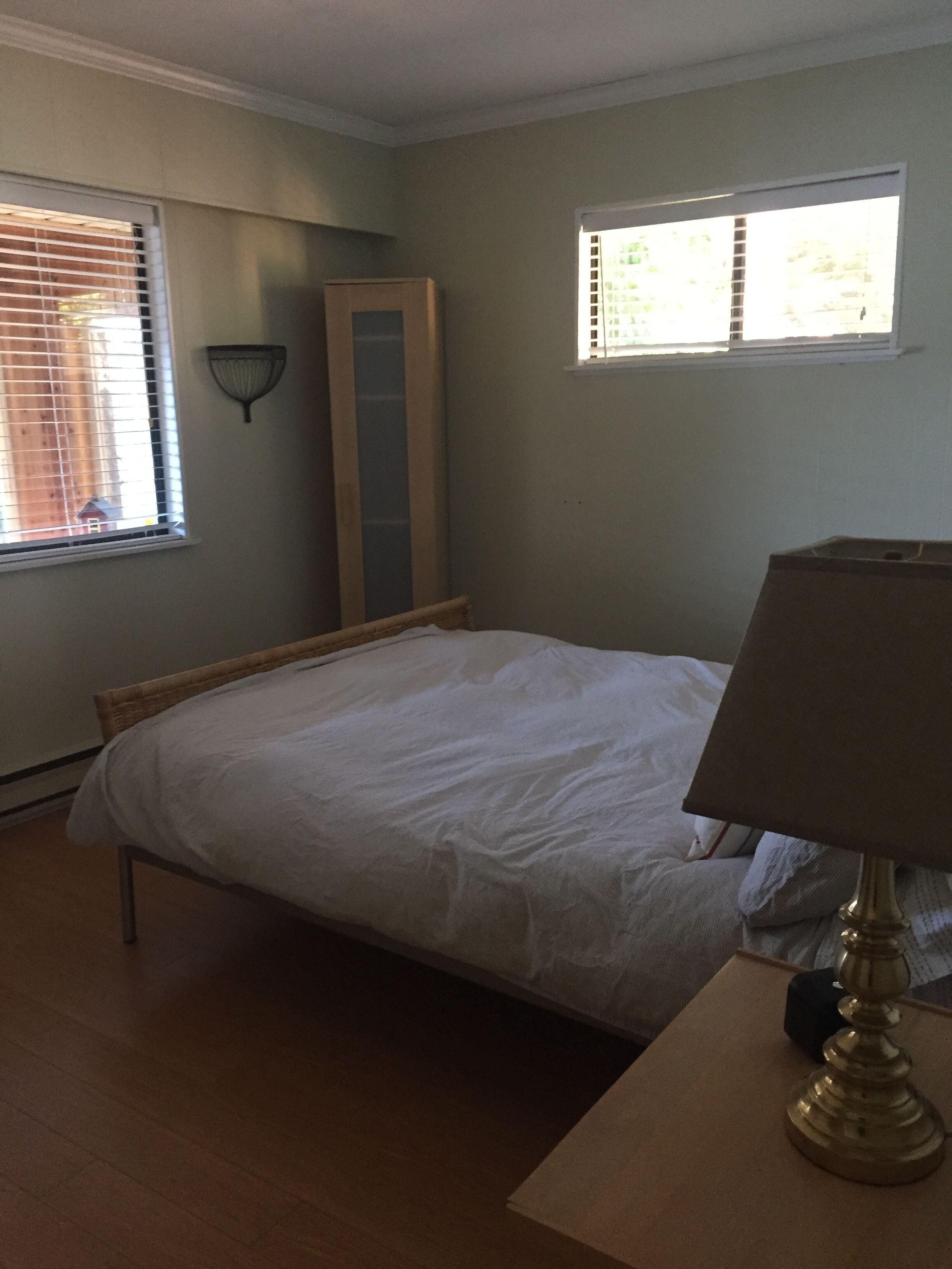 Een slaapkamer met een bed, een lamp, een raam en een deur.