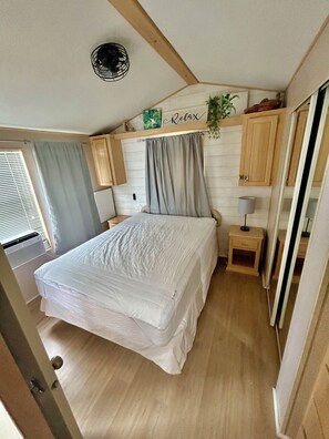 Una camera da letto con un letto, un comodino, una lampada e una ventola a soffitto.