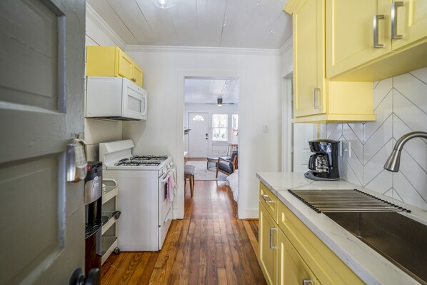 A kitchen with yellow cabinets, a white stove, and a sink.