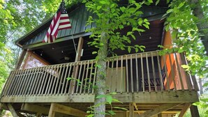 A wooden cabin with a balcony and an American flag. - Butterfly Ridge at Avenwood Cabins (New Straitsville)