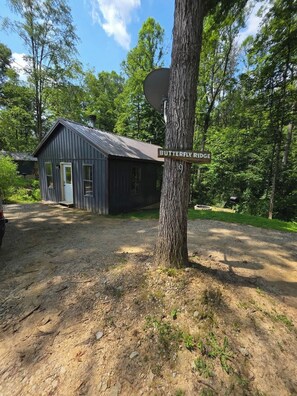 A rustic cabin labeled 'Butterfly Ridge' with a gravel driveway and surrounding trees.