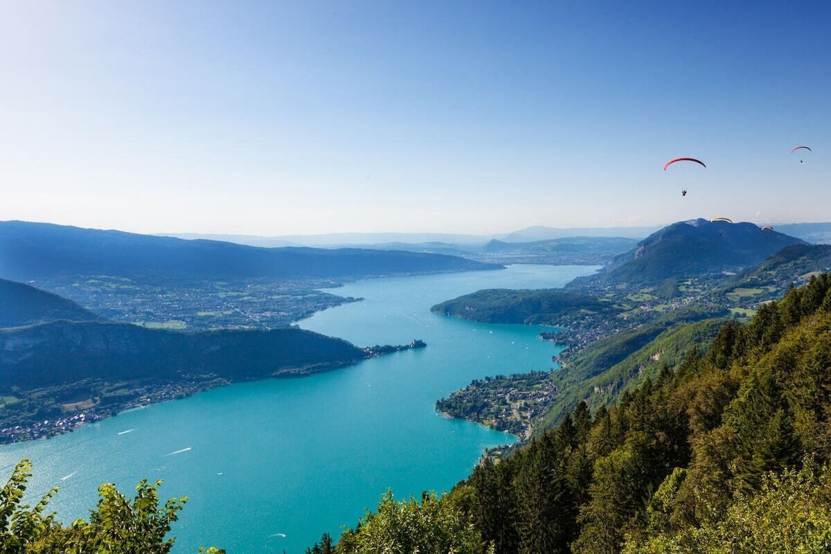 Een panoramisch uitzicht op een meer, omgeven door bergen en een stad.