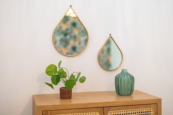 A wooden cabinet with a woven basket and a green vase, two wall mirrors, and a potted plant. - LakeView 2 - Premium Annecy - Veyrier du Lac (Veyrier-du-Lac)