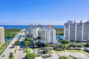A high-rise hotel with multiple floors, a swimming pool, and a view of the ocean.