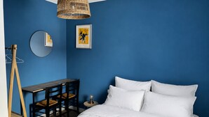 Een slaapkamer met een bed, een bureau, een stoel, een spiegel en een hanglamp.