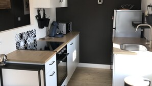 Een moderne keuken met witte kasten, een zwart aanrecht en een houten vloer.