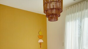 Ett sovrum med en säng, kuddar, en väggmonterad lampa och ett fönster med gardiner.