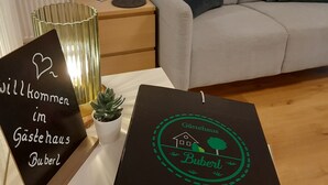 Un salon avec un canapé, une petite table sur laquelle est posée une plante en pot, et deux panneaux d’accueil.