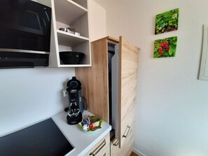 A compact kitchen with a coffee maker, a microwave, and a cabinet with a basket. - Guesthouse Buberl, near Legoland and Skylinepark (Krumbach (Schwaben))
