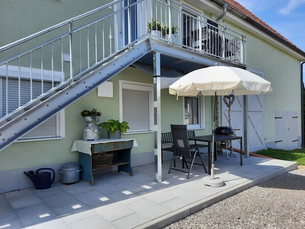 A balcony with a metal railing, a table with chairs, a white umbrella, and potted plants. - Guesthouse Buberl, near Legoland and Skylinepark (Krumbach (Schwaben))
